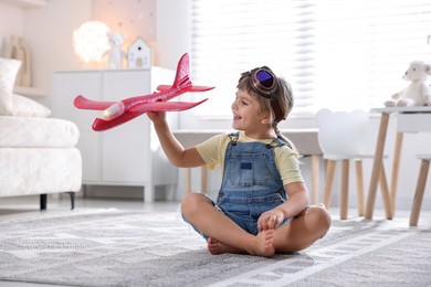 Photo of Cute little girl playing with toy plane at home