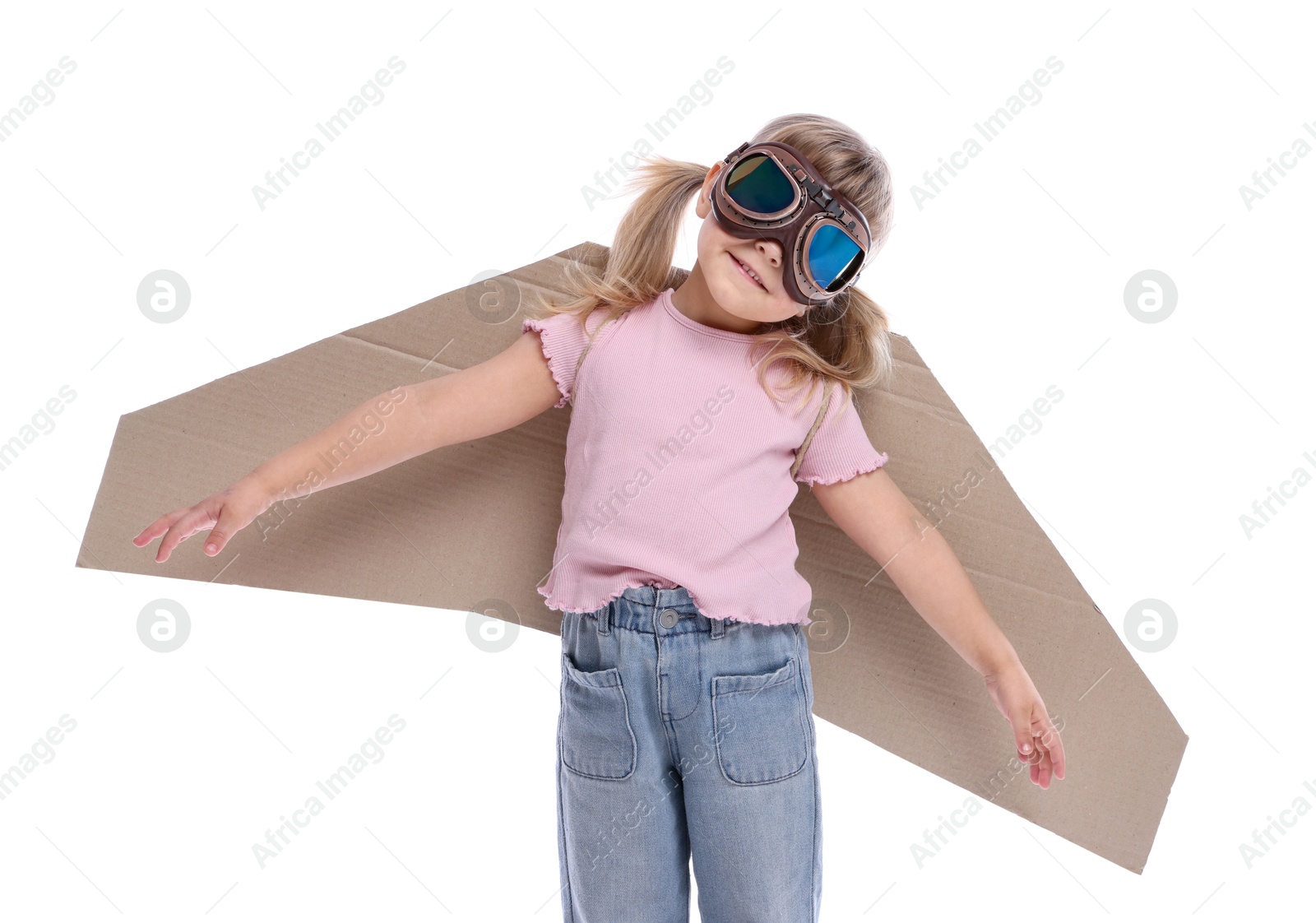 Photo of Cute little girl with cardboard plane wings and goggles playing pilot on white background