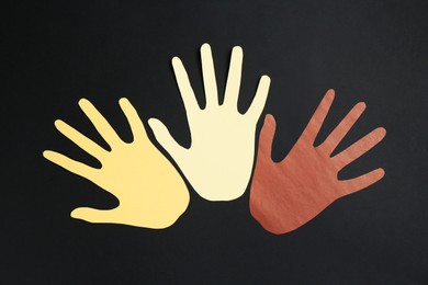 Photo of Stop racism. Hands paper figures of different colors on black background, top view