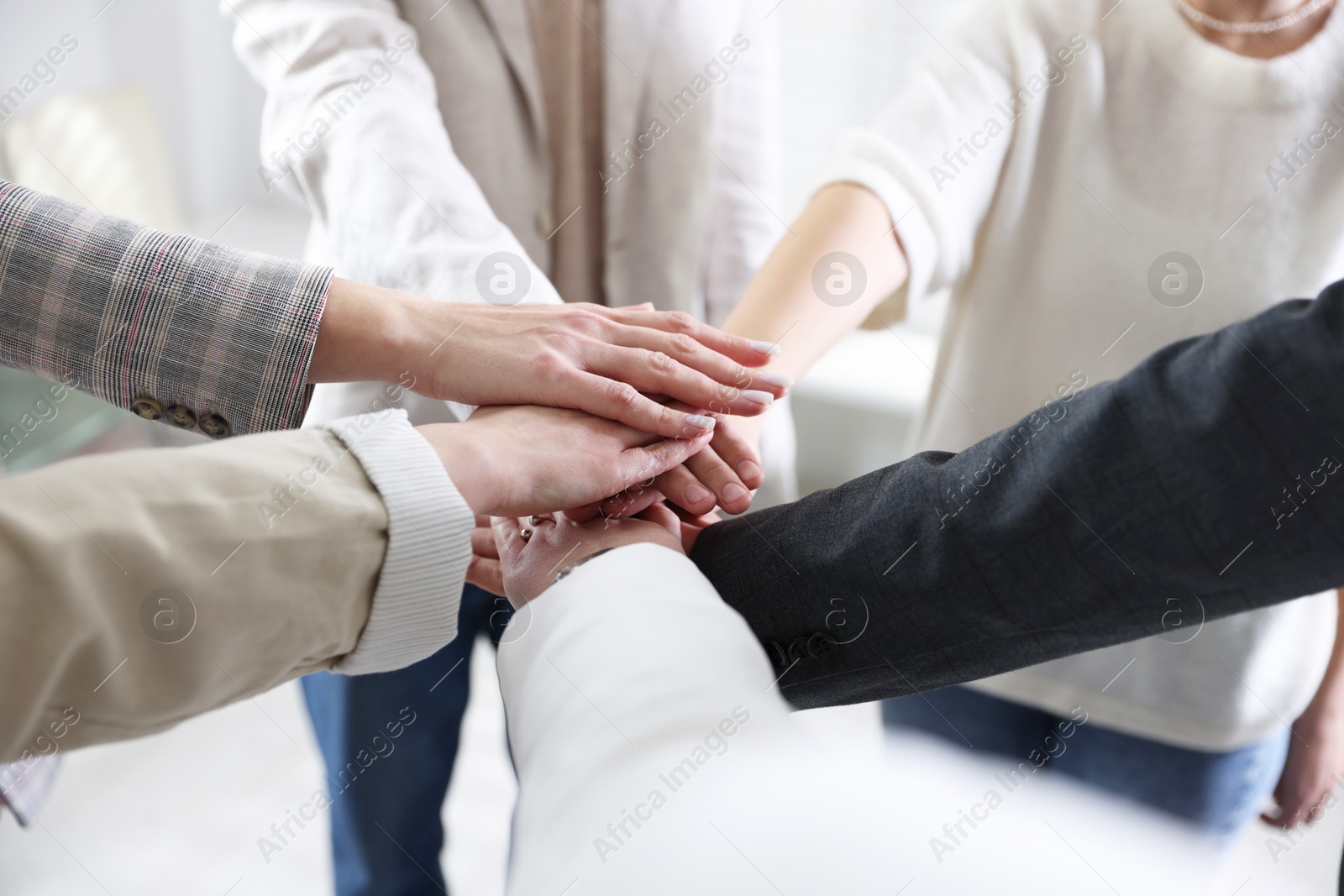 Photo of Unity concept. People holding hands together indoors, closeup