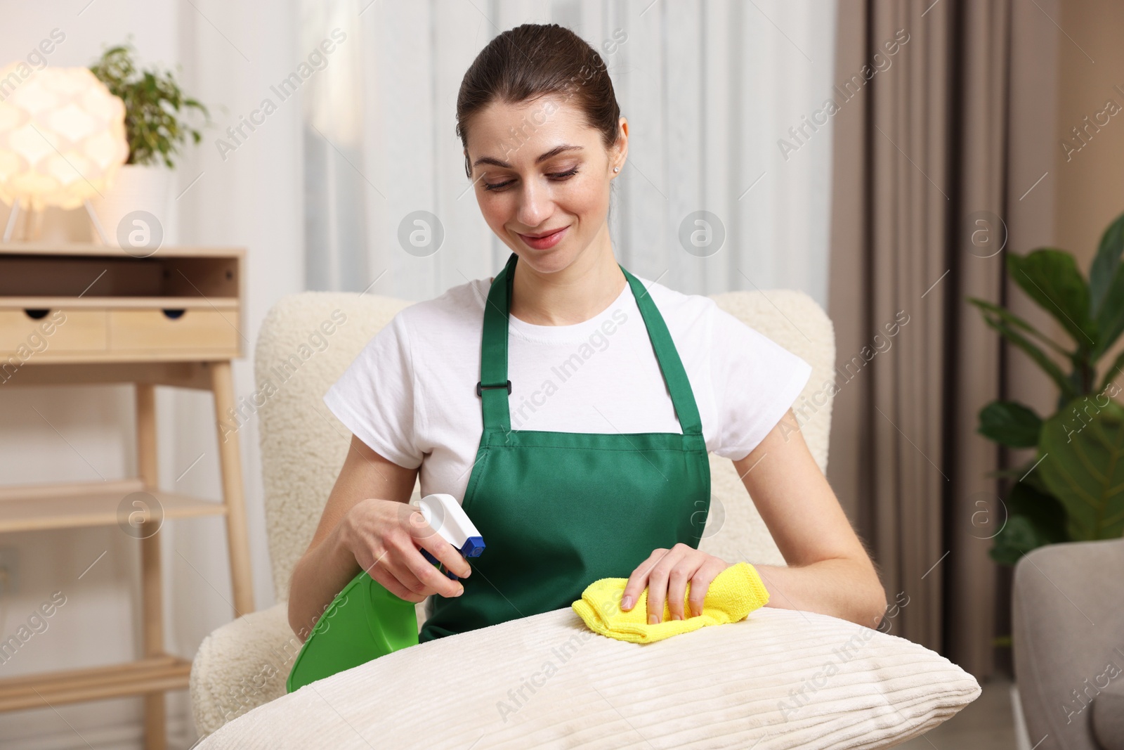 Photo of Janitor cleaning sofa cushion with rag at home