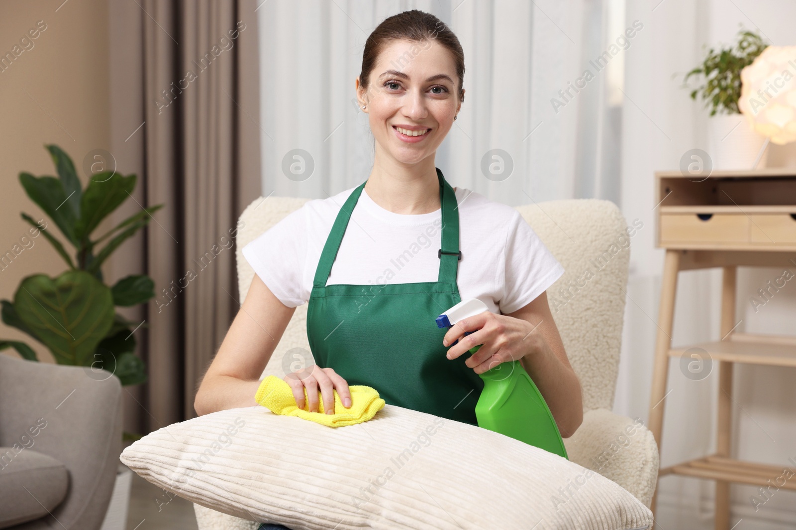 Photo of Janitor cleaning sofa cushion with rag at home