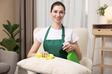 Photo of Janitor cleaning sofa cushion with rag at home