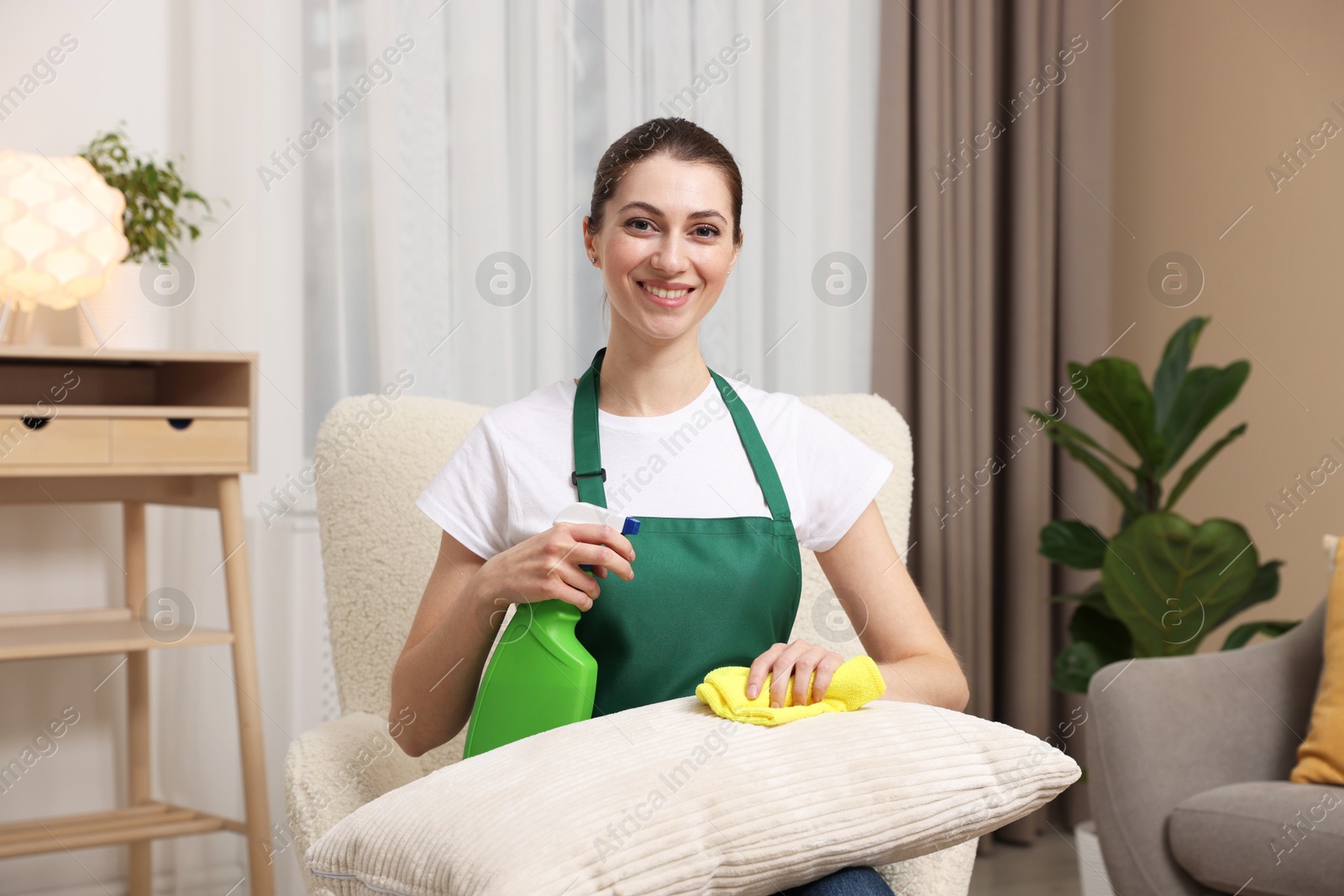 Photo of Janitor cleaning sofa cushion with rag at home