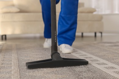 Photo of Cleaning service worker vacuuming rug with professional hoover at home, closeup