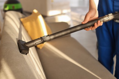 Photo of Professional janitor cleaning sofa with vapor steam system at home, closeup