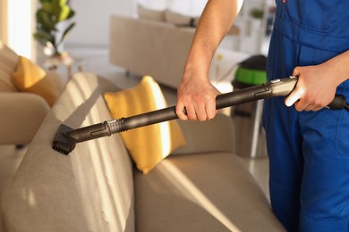 Photo of Professional janitor cleaning sofa with vapor steam system at home, closeup