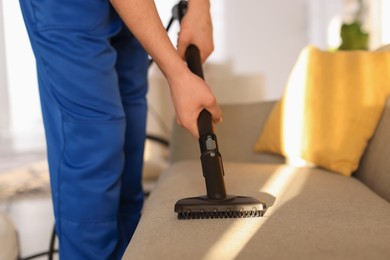 Photo of Professional janitor cleaning sofa with vapor steam system at home, closeup