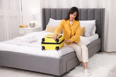 Photo of Woman unpacking suitcase on bed in hotel room