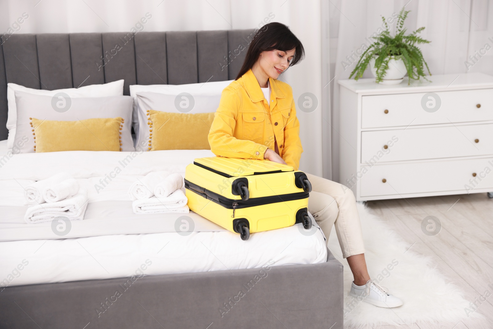 Photo of Woman unpacking suitcase on bed in hotel room