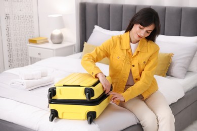 Photo of Woman unpacking suitcase on bed in hotel room