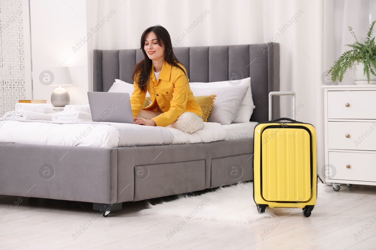 Photo of Woman with laptop on bed in her hotel room