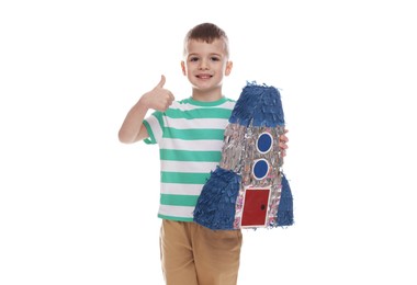 Photo of Happy boy with rocket shaped pinata showing thumbs up on white background