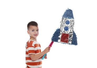 Photo of Happy boy breaking rocket shaped pinata with stick on white background