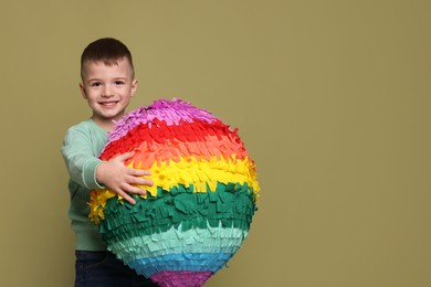 Photo of Happy boy with colorful pinata on olive color background. Space for text