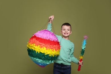 Photo of Happy boy with colorful pinata and stick on olive color background