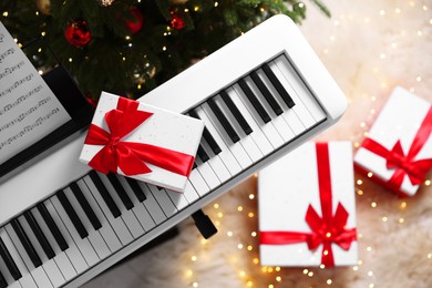 Photo of Synthesizer with gift boxes near Christmas tree indoors, top view