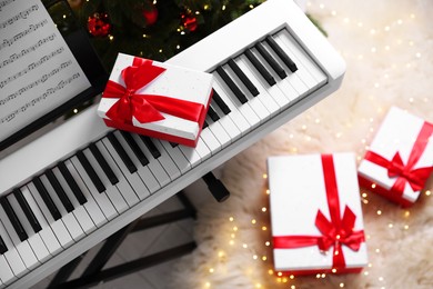 Photo of Synthesizer with gift boxes near Christmas tree indoors, top view