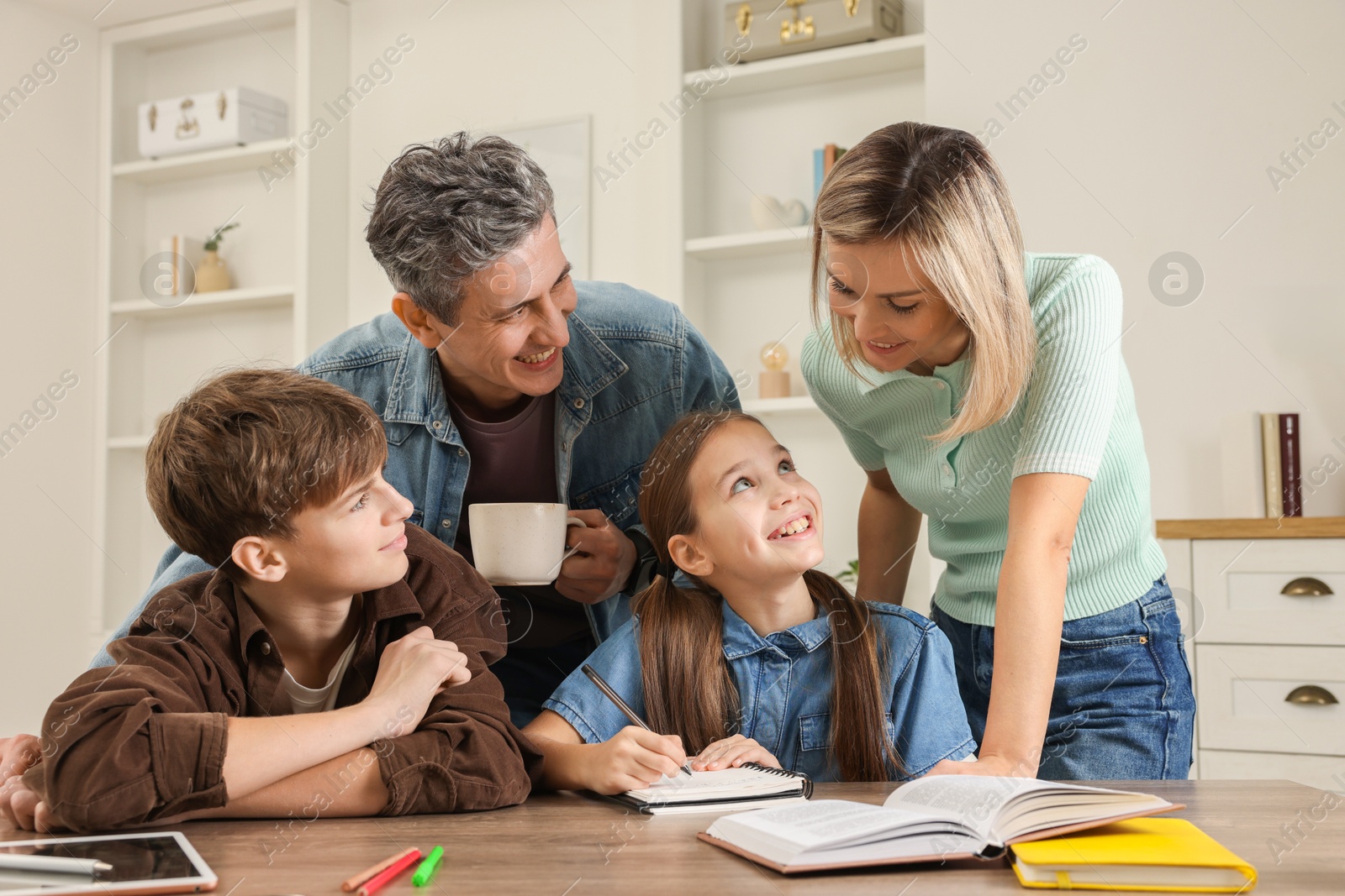 Photo of Happy parents and their children doing homework at table indoors