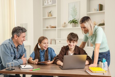 Photo of Happy parents and their children doing homework at table indoors