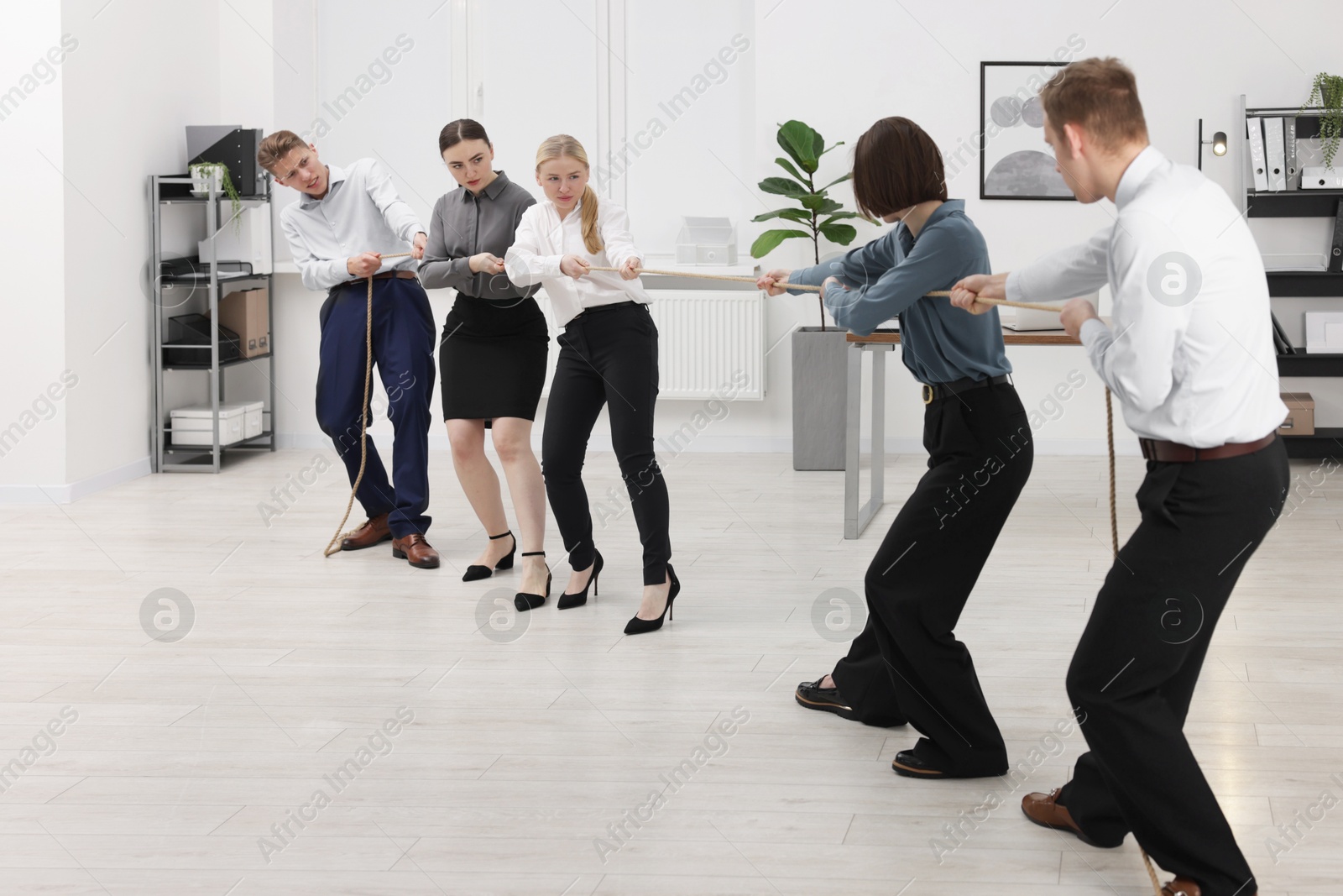 Photo of Competition concept. Group of businesspeople pulling rope in office