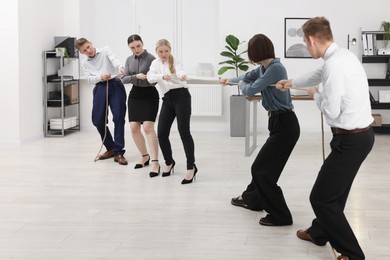 Photo of Competition concept. Group of businesspeople pulling rope in office