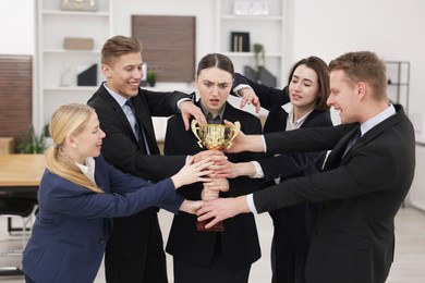 Photo of Competition concept. Group of businesspeople with golden trophy in office