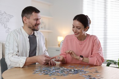 Photo of Couple solving puzzle together at wooden table indoors