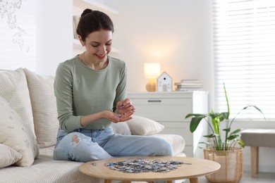 Photo of Happy woman solving puzzle at wooden table indoors, space for text