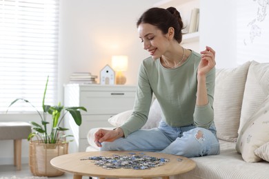 Photo of Happy woman solving puzzle at wooden table indoors, space for text