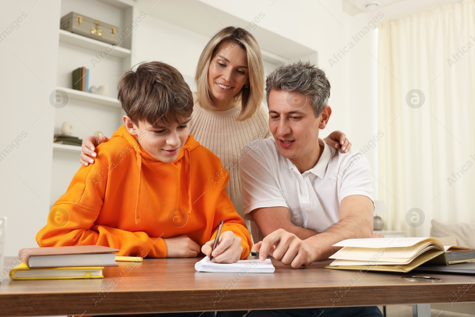 Photo of Parents helping their son with homework at table indoors, low angle view