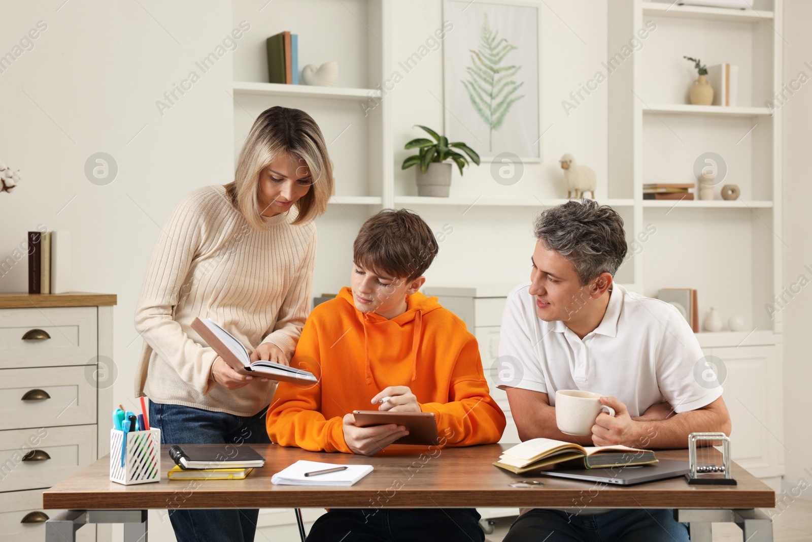 Photo of Parents helping their son with homework at table indoors