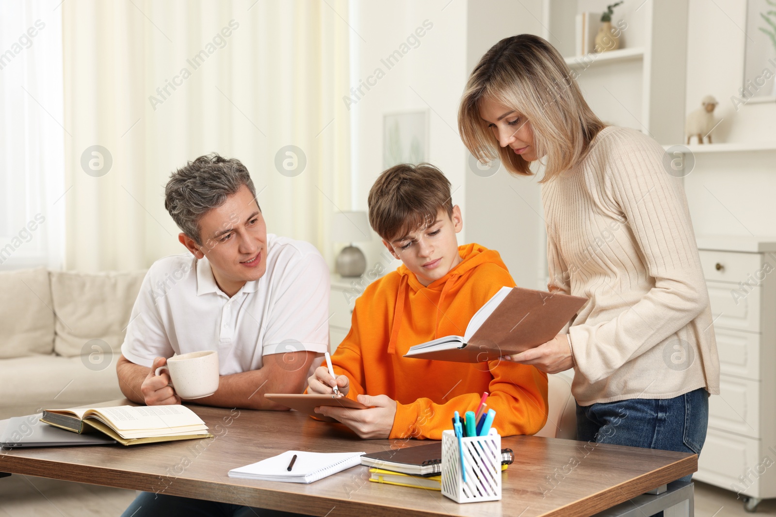 Photo of Parents helping their son with homework at table indoors