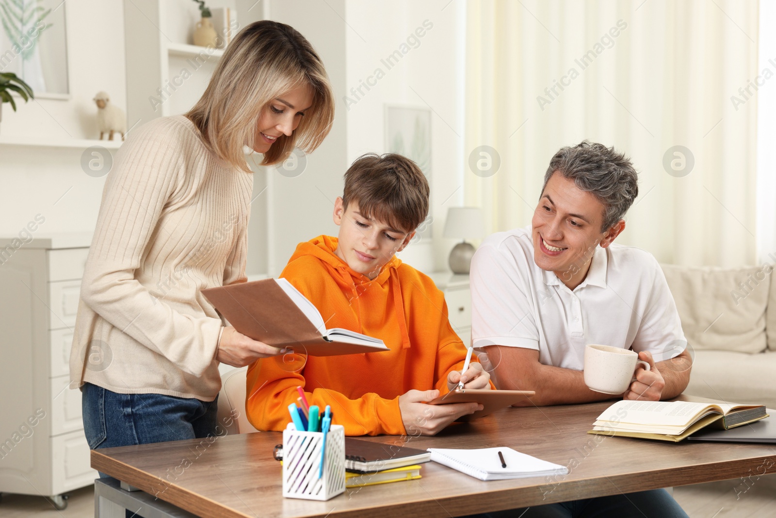 Photo of Parents helping their son with homework at table indoors