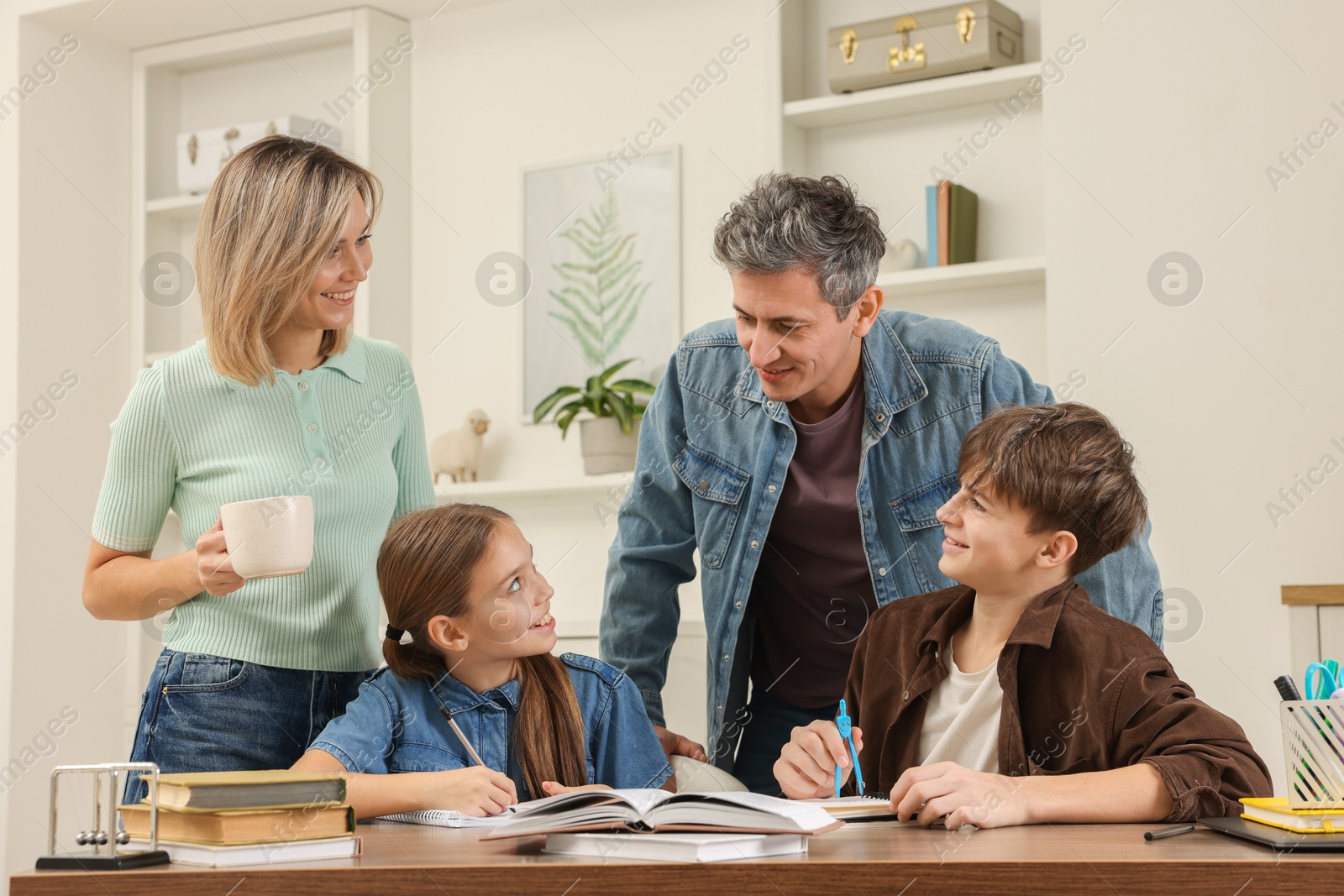 Photo of Parents helping their children with homework at table indoors