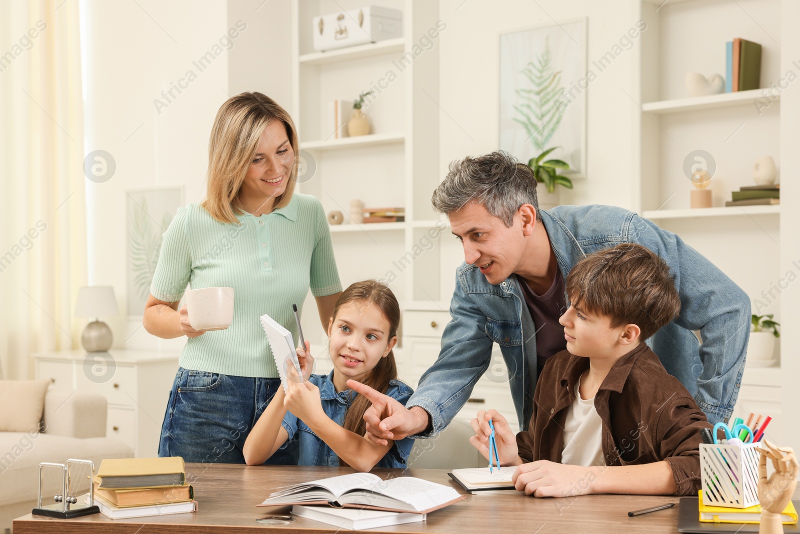 Photo of Parents helping their children with homework at table indoors