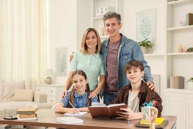 Photo of Parents and their children doing homework at table indoors