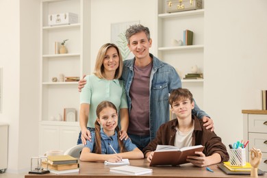 Photo of Parents and their children doing homework at table indoors