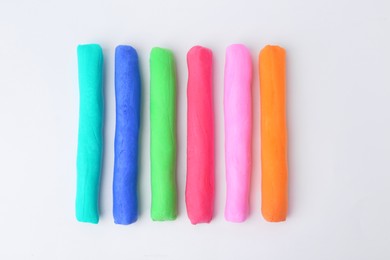 Photo of Different colorful play dough on white background, flat lay