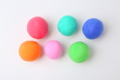 Photo of Different colorful play dough balls on white background, flat lay