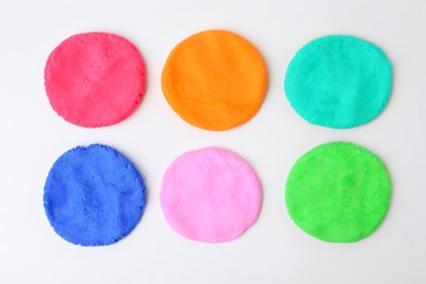 Photo of Different colorful play dough on white background, flat lay