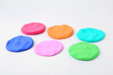 Photo of Different colorful play dough on white background, closeup