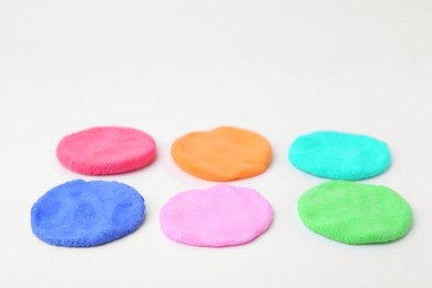 Photo of Different colorful play dough on white background, closeup