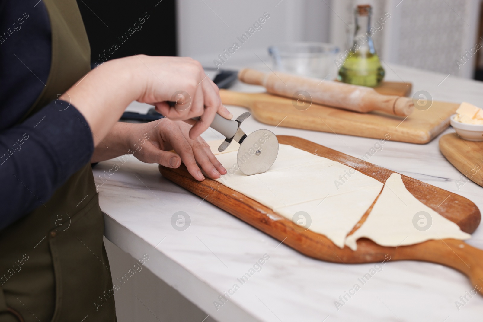 Woman cutting dough at light marble table indoors, closeup. Making croissants Photo of Woman cutting dough at light marble table indoors, closeup. Making croissants