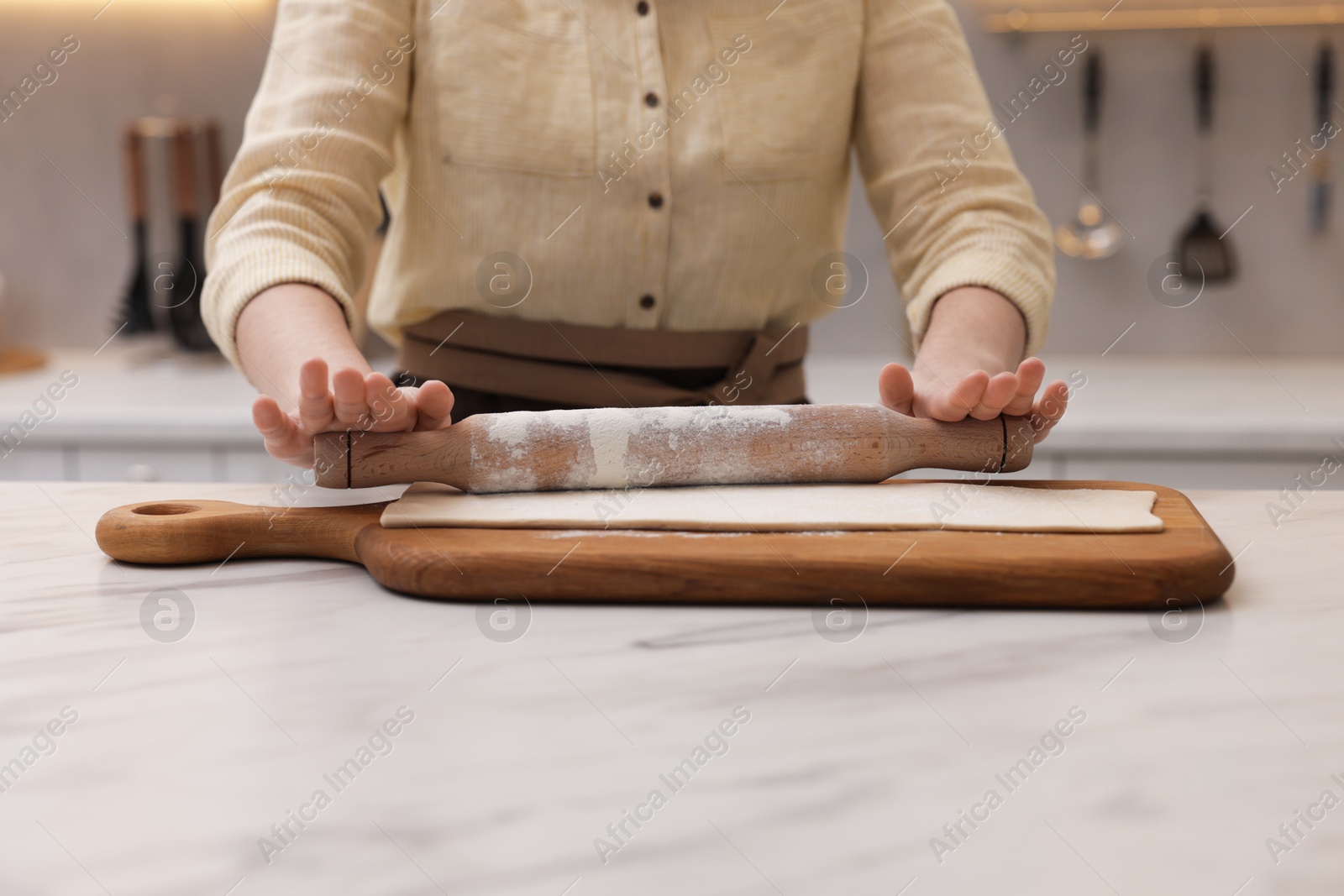 Woman rolling dough at light marble table indoors, closeup. Making croissants Photo of Woman rolling dough at light marble table indoors, closeup. Making croissants