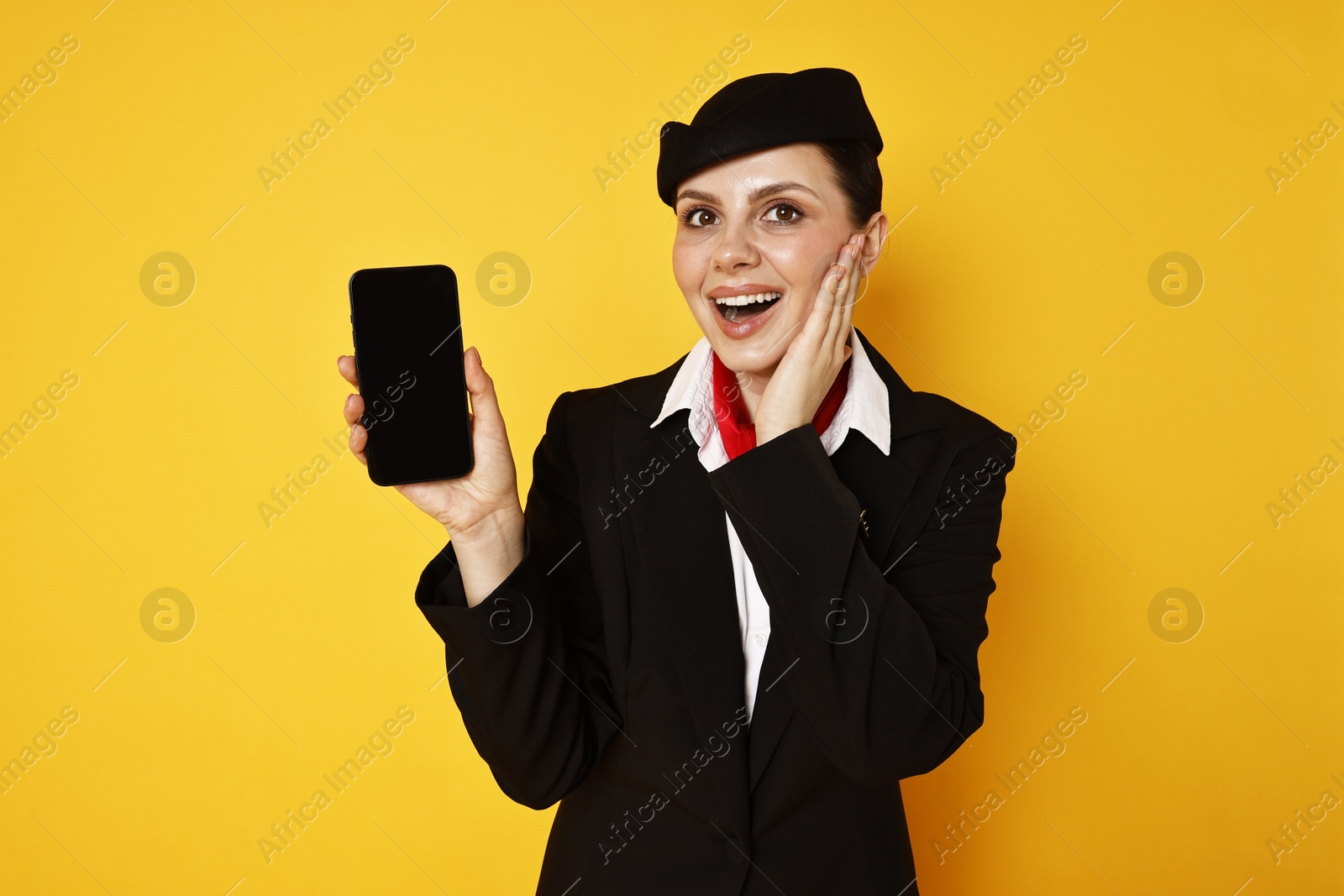 Photo of Excited stewardess with smartphone on orange background