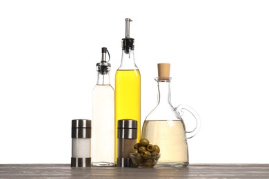 Photo of Salad dressings, spices and olives on wooden table against white background