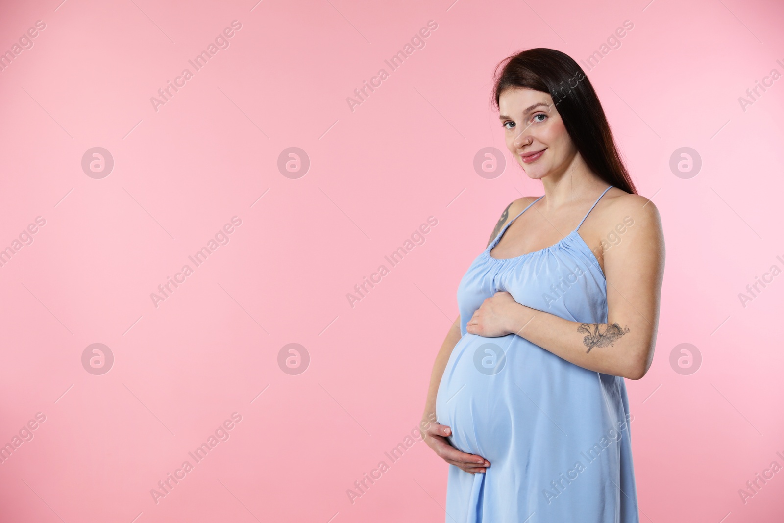 Photo of Beautiful pregnant woman with cute belly on pink background. Space for text