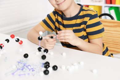 Photo of Boy making DNA structure model at desk indoors, closeup