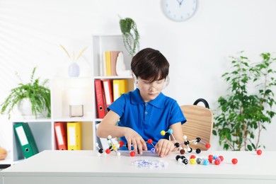 Photo of Boy making DNA structure model at desk indoors